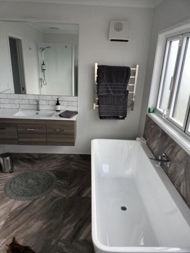 a bathroom with a large white tub and a sink at Opotiki Waiotahi Beach Retreat in Opotiki