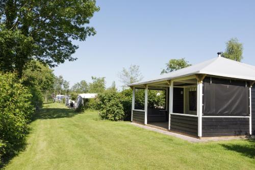 a gazebo with a white roof in a yard at Familiecamping De Vossenburcht in IJhorst