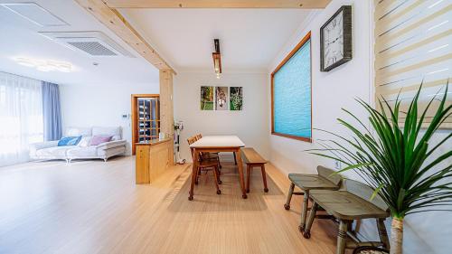 ein Wohnzimmer mit einem Tisch, Stühlen und einem Sofa in der Unterkunft Moon Drawing Goeun in Chuncheon