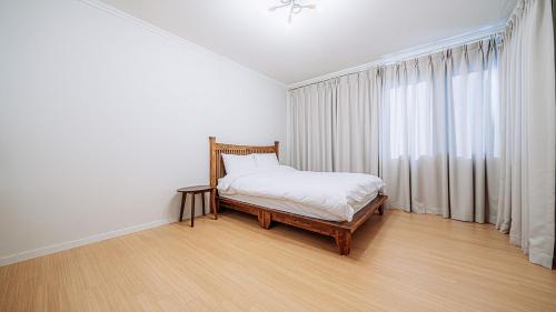 a white bedroom with a bed and a window at Moon Drawing Goeun in Chuncheon