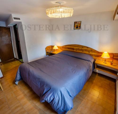 a large bed in a bedroom with a chandelier at Hosteria El Aljibe in San Carlos de Bariloche