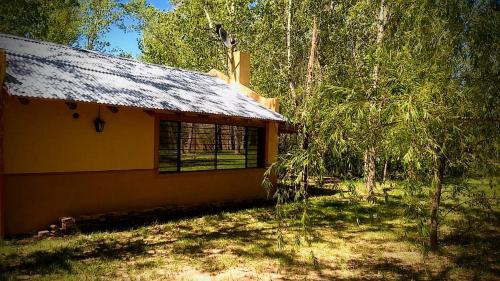 una casa amarilla con techo de estaño en un bosque en La CUEVA DEL OSO en San Rafael