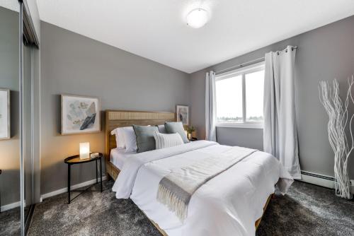 a bedroom with two beds and a large window at Peaceful Oasis Condo, AC, Top Floor, Secure UG Parking, Balcony, King Bed! in Edmonton