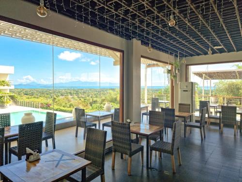 a restaurant with tables and chairs and large windows at Panja Resort Palawan in Puerto Princesa City