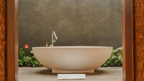 a white bath tub sitting in front of a wall at Annora Villas Seminyak in Seminyak