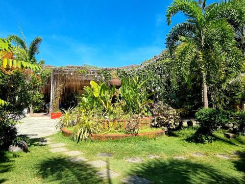 ogród z drzewami i roślinami przed budynkiem w obiekcie Buddha Resort by Cocotel w mieście Bugallon