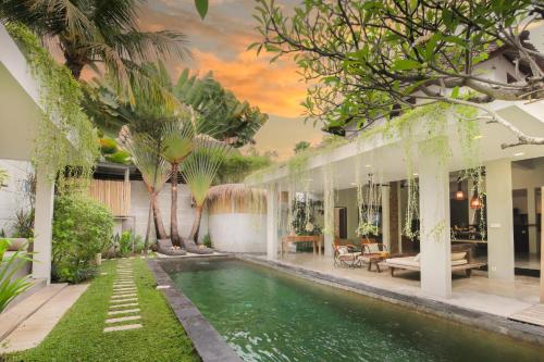 a swimming pool in the backyard of a house with trees at Villa Malou in Seminyak