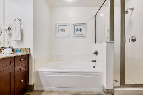 a white bathroom with a tub and a shower at AQUA RESORT! Beachfront, 3 Bedroom Condo! 2 Bedrooms Beach Front! Sleeps 7! Free Beach Chairs by Dolce Vita Getaways PCB in Panama City Beach