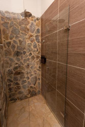 a bathroom with a shower with a stone wall at Entre Palmas Casa Hotel in Santa Fe de Antioquia