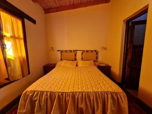 a bedroom with a bed with a yellow bedspread at Hostería La Enramada in Seclantás
