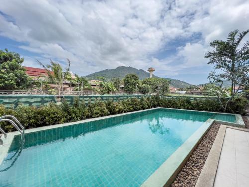a pool at a resort with mountains in the background at Melissa Kata Beach Resort in Kata Beach