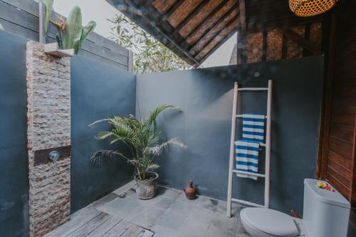 La salle de bains est pourvue de toilettes et d'un mur bleu. dans l'établissement Dream Beach Huts, à Nusa Lembongan