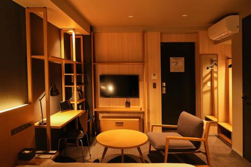 um pequeno quarto com uma secretária, uma mesa e cadeiras em N Plus Hotel Akihabara em Tóquio