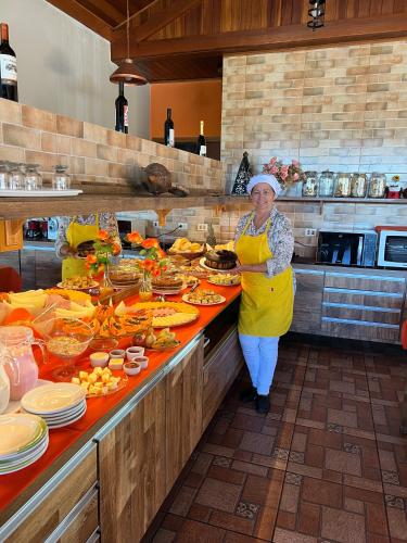 una donna in piedi in cucina che prepara il cibo di Pousada Heron a Campos do Jordão