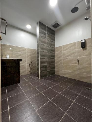 La salle de bains est pourvue d'une douche et de carrelage. dans l'établissement Roomah Istana, à Ipoh