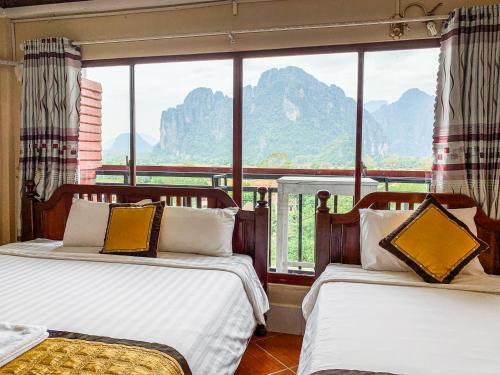 two beds in a room with a view of mountains at Bountang Mountain View Riverside Hotel in Vang Vieng