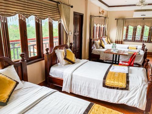 a hotel room with two beds and a table at Bountang Mountain View Riverside Hotel in Vang Vieng