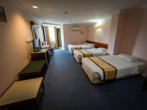 a hotel room with two beds and a television at Miri Hotel in Miri