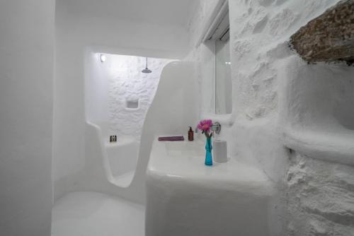 a white bathroom with a vase with a pink flower in it at Rocky Mansion in Agrari