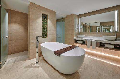 a bathroom with a large white tub and a mirror at Angsana Teluk Bahang in Batu Ferringhi