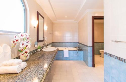 a bathroom with a sink and a bath tub at Stella Stays Brilliant 4 BDR Palm Villa Beach Private Pool in Dubai