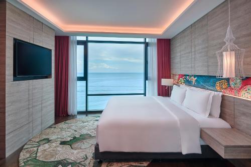 a bedroom with a large white bed and a large window at Angsana Teluk Bahang, Penang in Batu Ferringhi