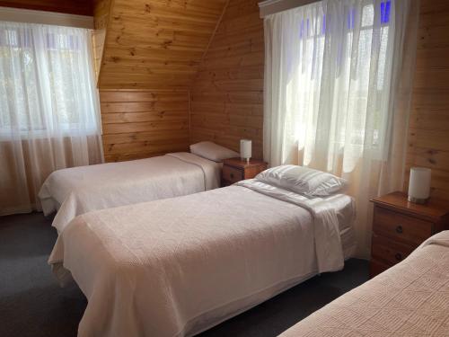 Duas camas num quarto com paredes e janelas de madeira em Sails - elegant, spacious beach villa em Port Fairy