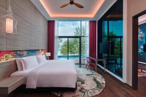 a bedroom with a large white bed and a large window at Angsana Teluk Bahang in Batu Ferringhi