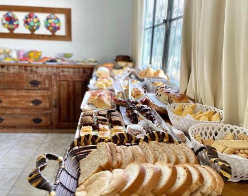 um buffet de pão e produtos de pastelaria numa mesa em Pouso das Flores -350m Maria Fumaça em Tiradentes