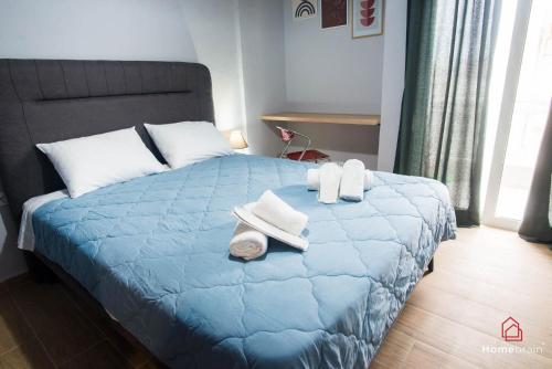 Un dormitorio con una cama azul con toallas. en Filoxenia apart by homebrain, en Alexandroupoli
