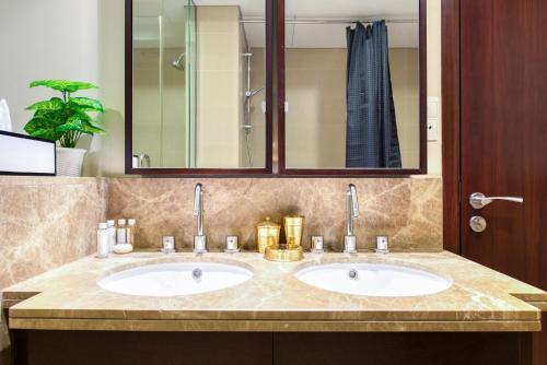 a bathroom with two sinks and a mirror at Maison Privee - Radiant Urban Retreat with Iconic Burj Khalifa Vws in Dubai