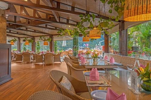 a restaurant with tables and chairs with pink napkins at Aloha On The Ganges by Leisure Hotels in Rishīkesh