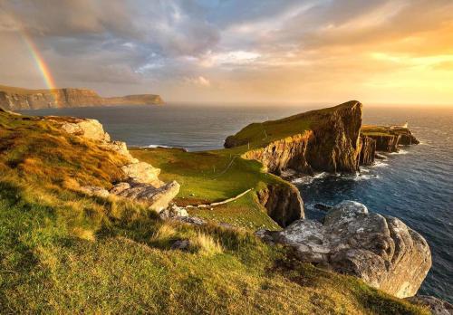 un arcobaleno sull'oceano con una costa rocciosa di Skye View Cottage a Portree