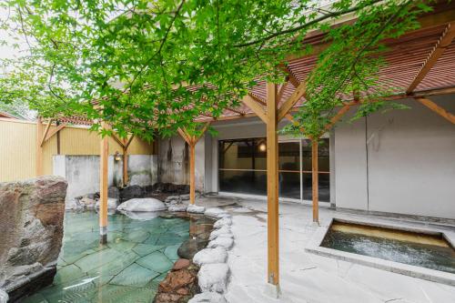 een tuin met een vijver en bomen voor een gebouw bij Yufuin Kotobuki Hananosho in Yufu