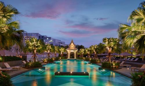 uma piscina no resort com palmeiras e um pagode em Chatrium Grand Bangkok em Bangkok