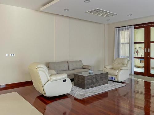 a living room with two chairs and a couch and a table at Merbau Luxurious Villa Senggigi by The Lavana - 5 Bedroom Villa in Mataram