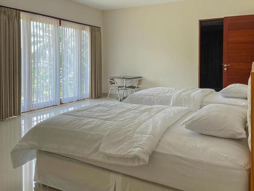 a large white bed in a bedroom with a table at Merbau Luxurious Villa Senggigi by The Lavana - 5 Bedroom Villa in Mataram