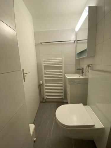 ein weißes Bad mit einem WC und einem Waschbecken in der Unterkunft Paradies 104 in Arosa