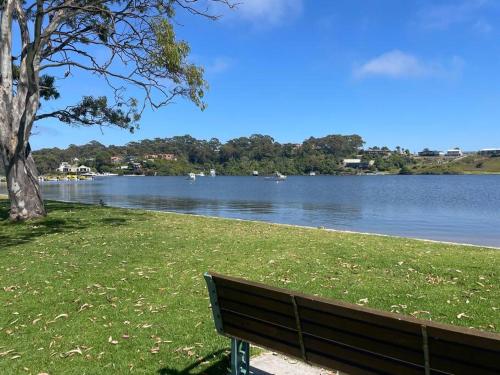 un banco del parque sentado frente a un lago en Skipper’s Lakes Entrance *Waterfront* en Lakes Entrance