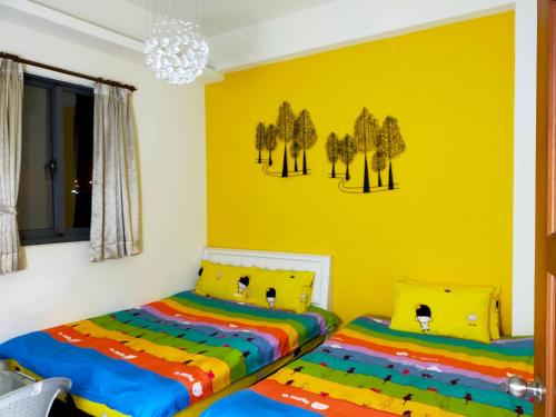 two beds in a room with a yellow wall at Qingyun Homestay in Toucheng