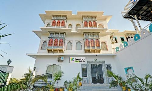 a large white building with red doors and windows at Treebo Trend Khakhri Haveli in Udaipur