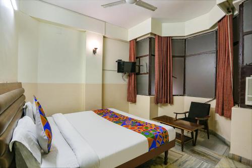 a bedroom with a bed and a chair and a tv at FabHotel Ashoka Inn in Kānpur