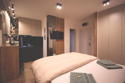 a bedroom with a large white bed and a kitchen at TOP Room in Šabac