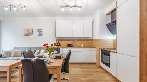 a kitchen and dining room with a wooden table and chairs at Plac Unii, Sun & Snow in Gdynia