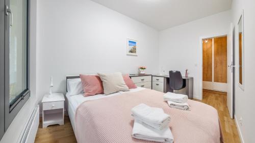 a white bedroom with a bed with towels on it at Plac Unii, Sun & Snow in Gdynia
