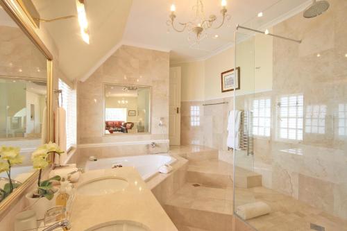 a bathroom with a tub and a sink and a shower at St James Guest Houses in Kalk Bay