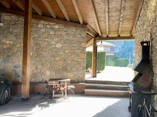 a patio with a table and a stone wall at Casa Riu in Riu de Cerdanya