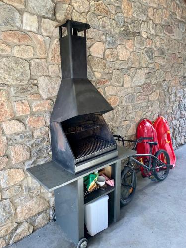 a grill with a bike parked next to a stone wall at Casa Riu in Riu de Cerdanya