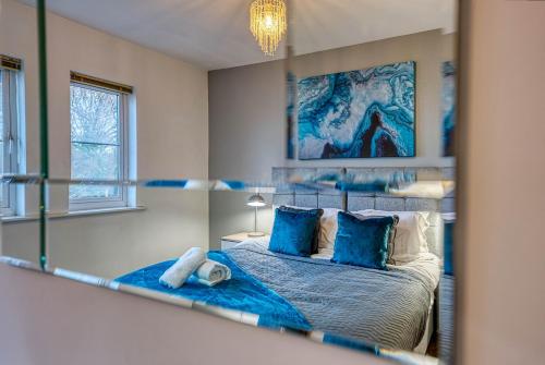 a bedroom with a bed with blue pillows and a mirror at Blue Cedar 2 Bed, 2 Bath Apt with Parking, Birmingham by 360Midlands in Sutton Coldfield