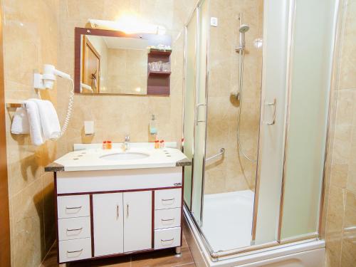 ein Badezimmer mit einem weißen Waschbecken und einer Dusche in der Unterkunft Hotel Petrovac in Petrovac na Moru